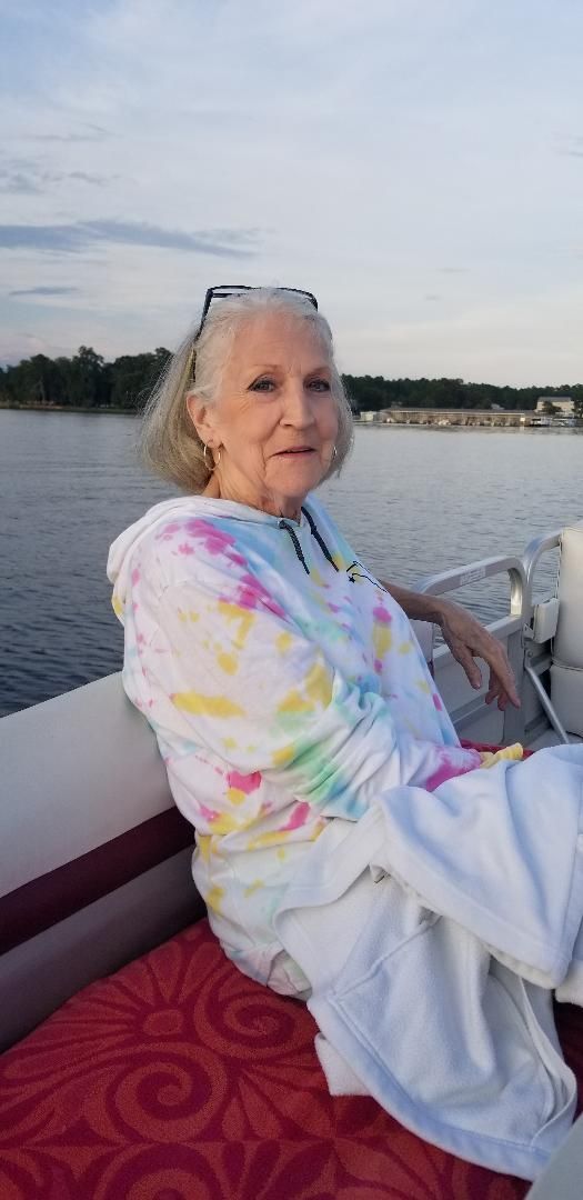 An elderly woman is sitting on a boat in the water.