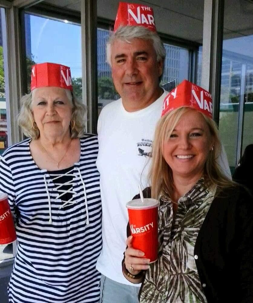 A man and two women wearing paper hats that say the nar