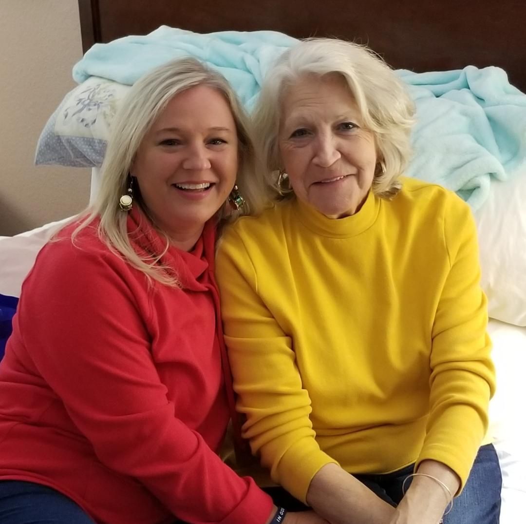 A woman in a yellow sweater sits next to another woman in a red sweater