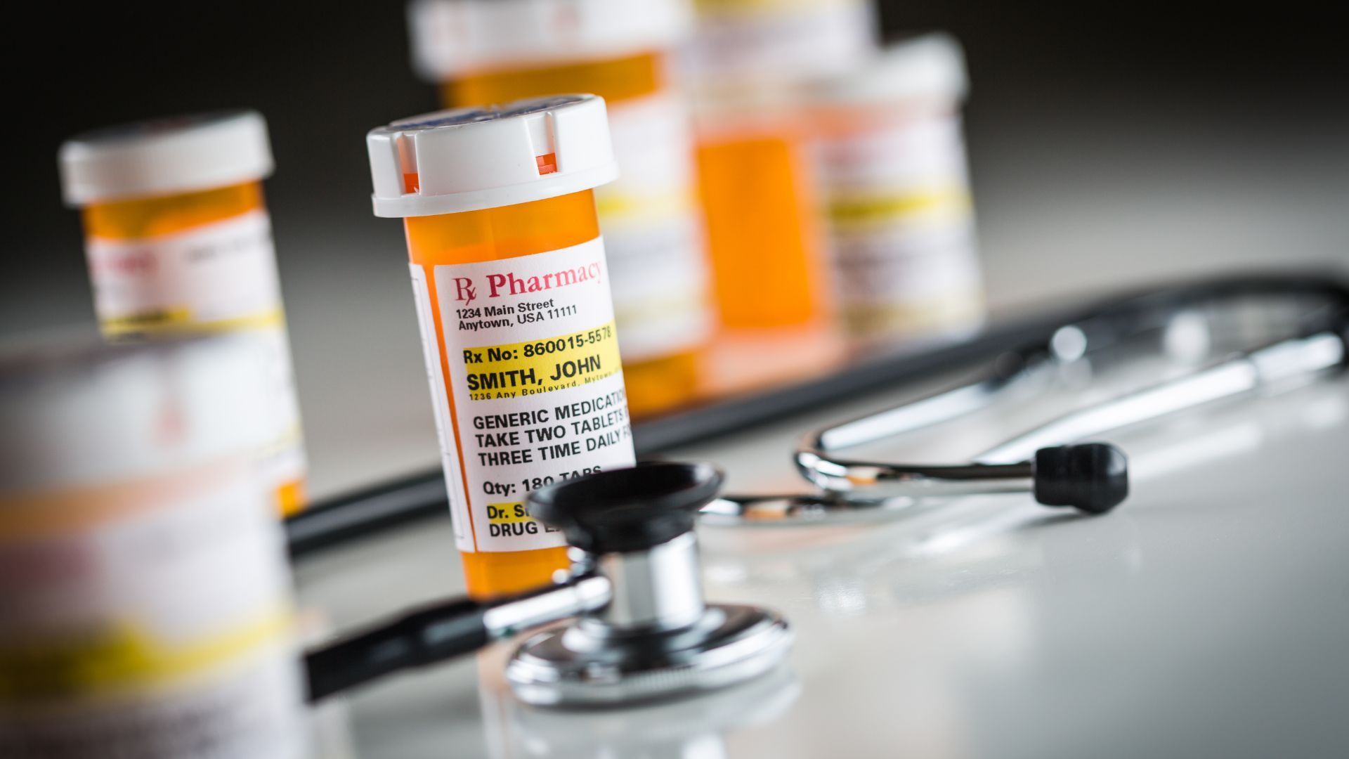 A bottle of pills and a stethoscope are on a table.