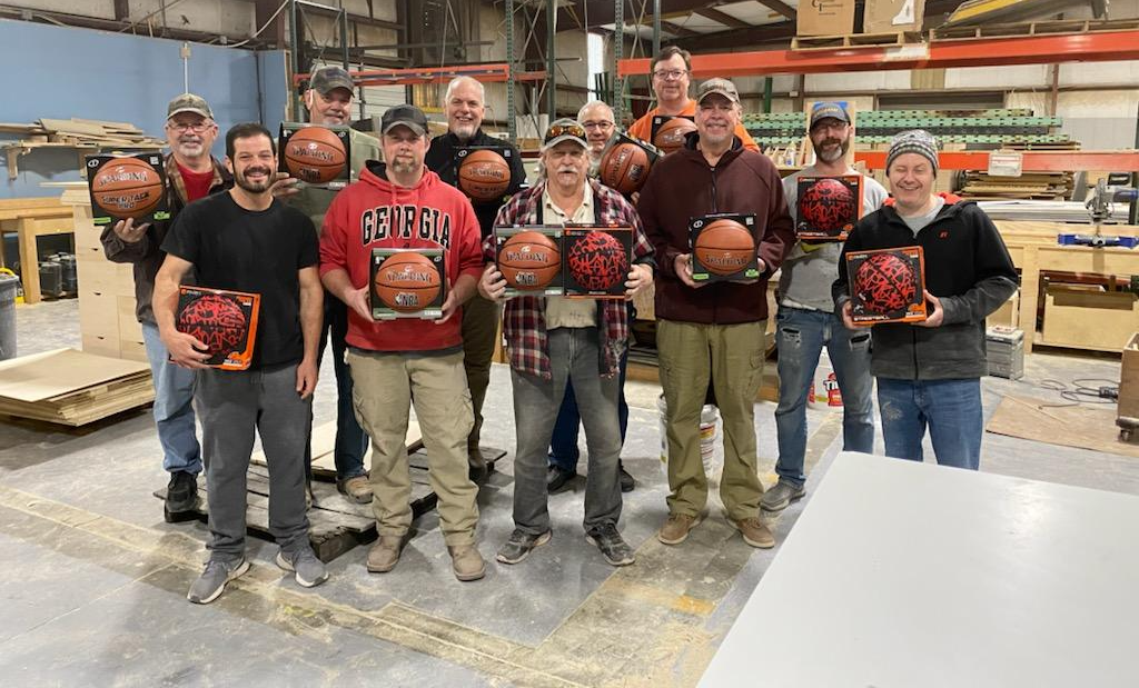 A group of men are standing in a warehouse holding basketballs.