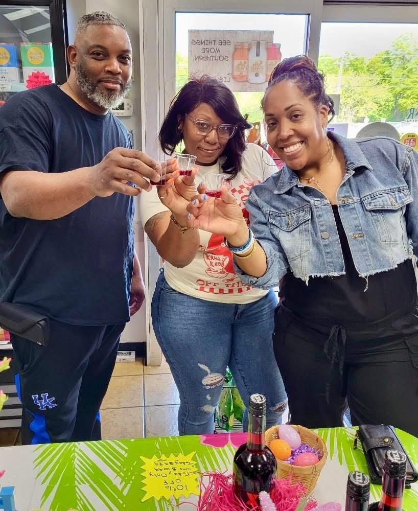 A group of people are standing around a table in a liquor store.