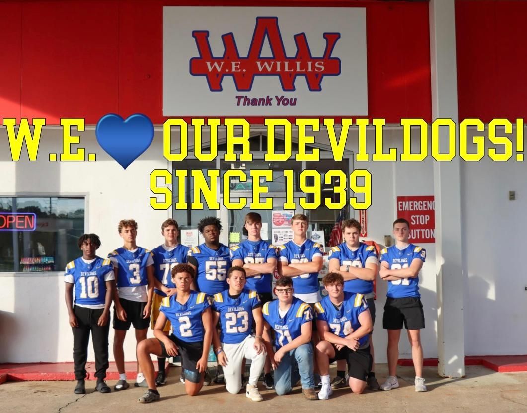 A group of young men are posing for a picture in front of a gas station.