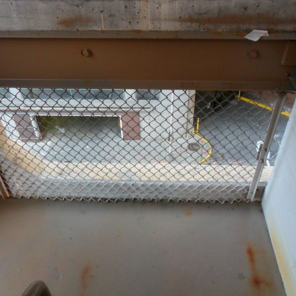 A balcony with a chain link fence overlooking a parking lot