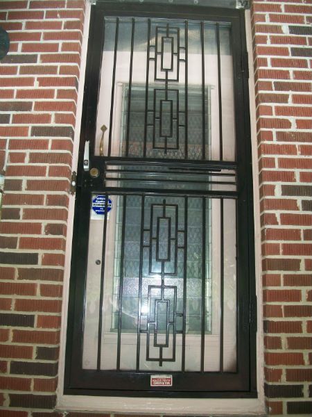 A wrought iron door with a brick wall behind it