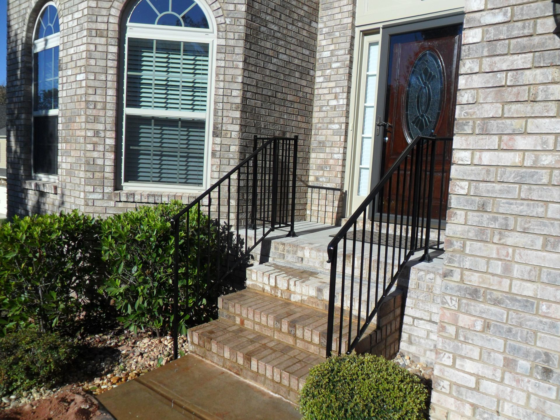 A brick house with a black railing and stairs