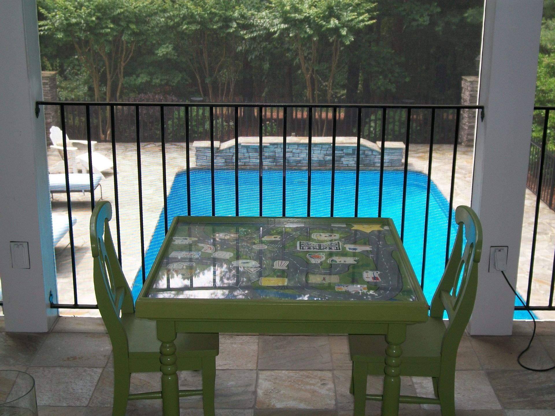 A table and chairs on a balcony overlooking a pool