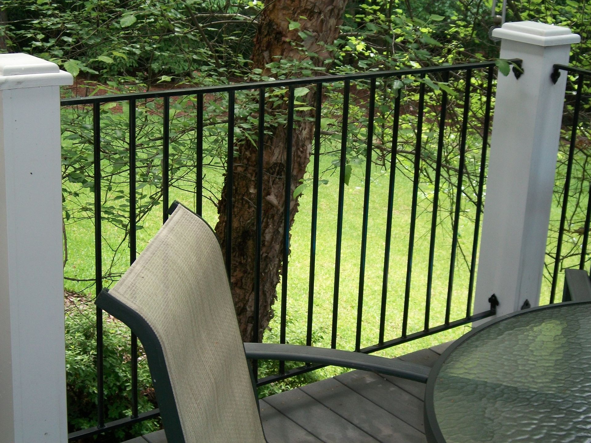 A table and chair on a deck with a fence in the background