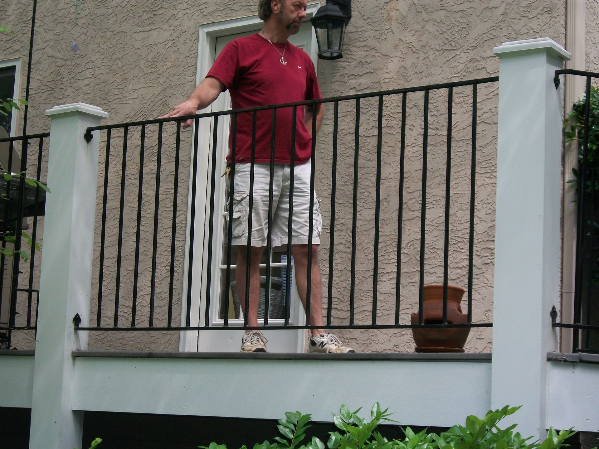 A man in a red shirt is standing on a balcony