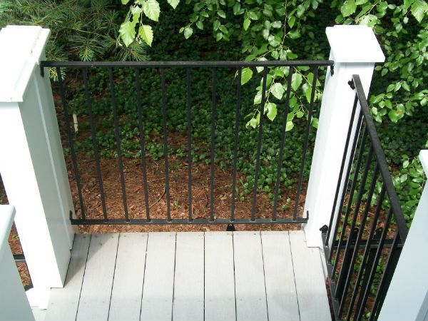 A black railing on a deck with trees in the background