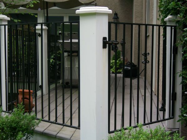 A white fence with a black gate leading to a deck