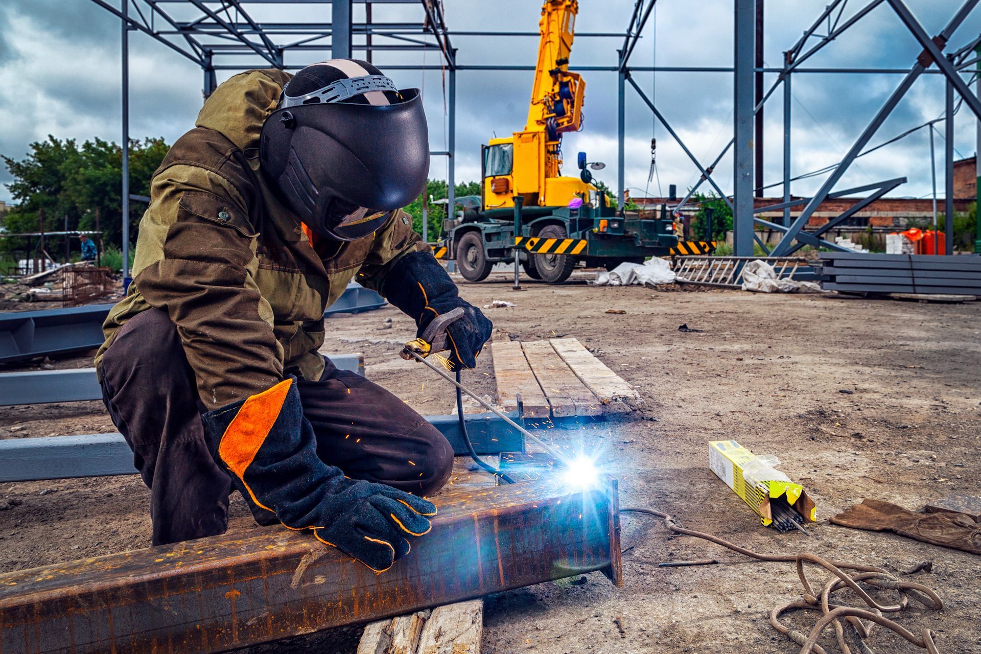 A man is welding a piece of metal on a construction site.