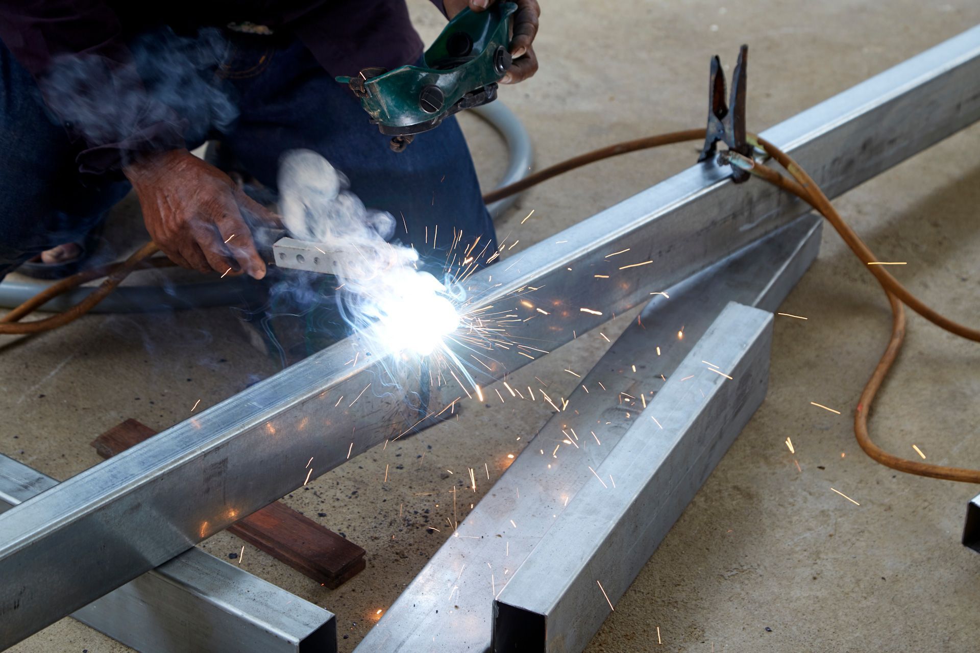 A man is welding a piece of metal with sparks coming out of it.