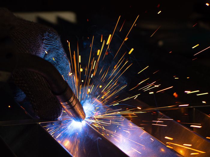 A person is welding a piece of metal with sparks coming out of it.