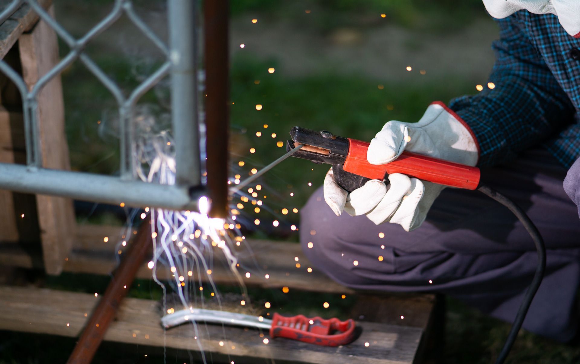 A man is welding a metal fence with a welding machine.