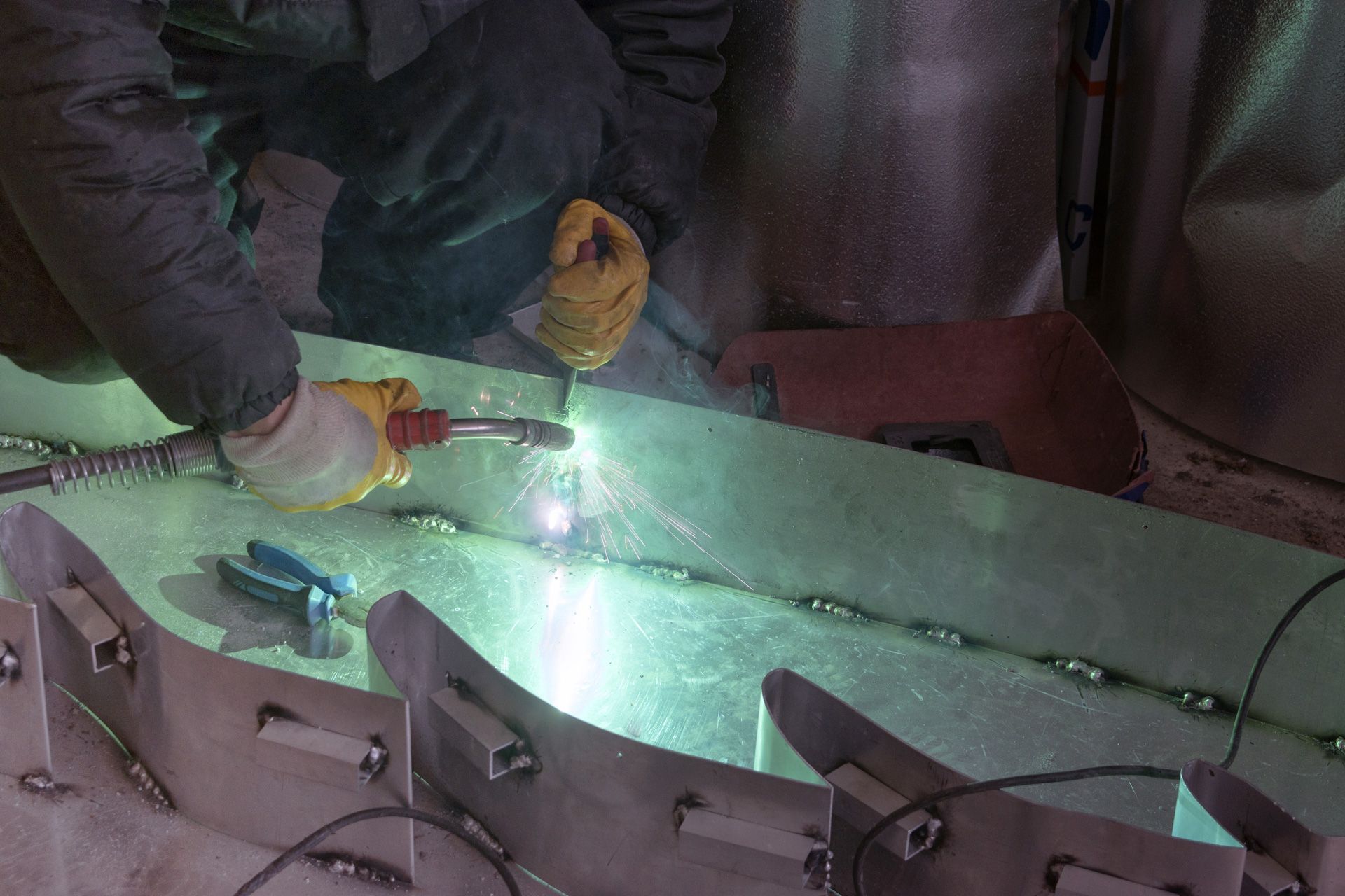 A man is welding a piece of metal in a factory.