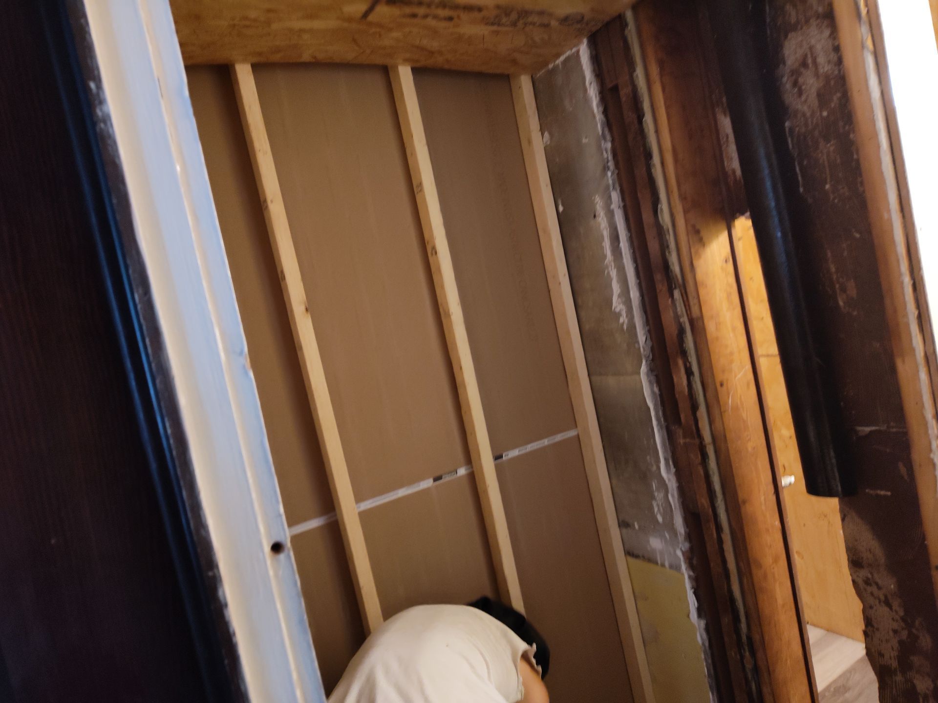 A man is kneeling down in a room with wooden walls