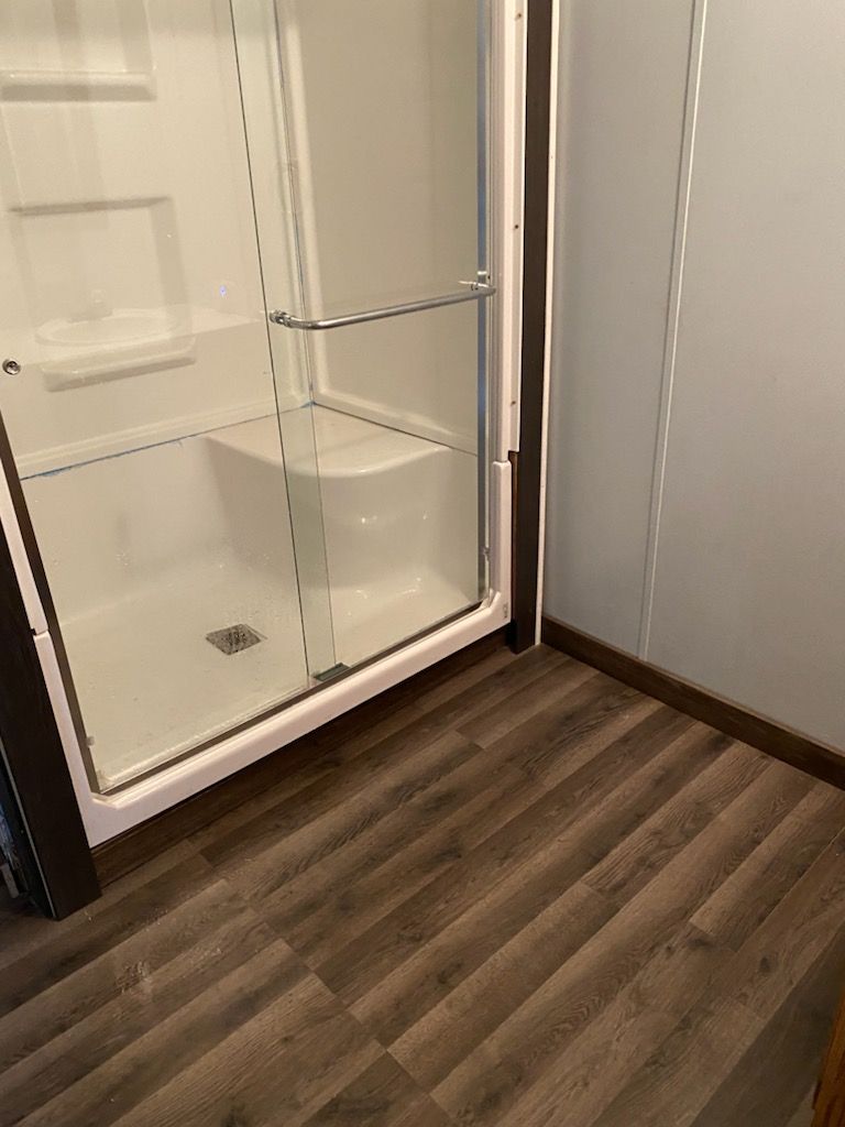 A bathroom with a walk in shower and a wooden floor.