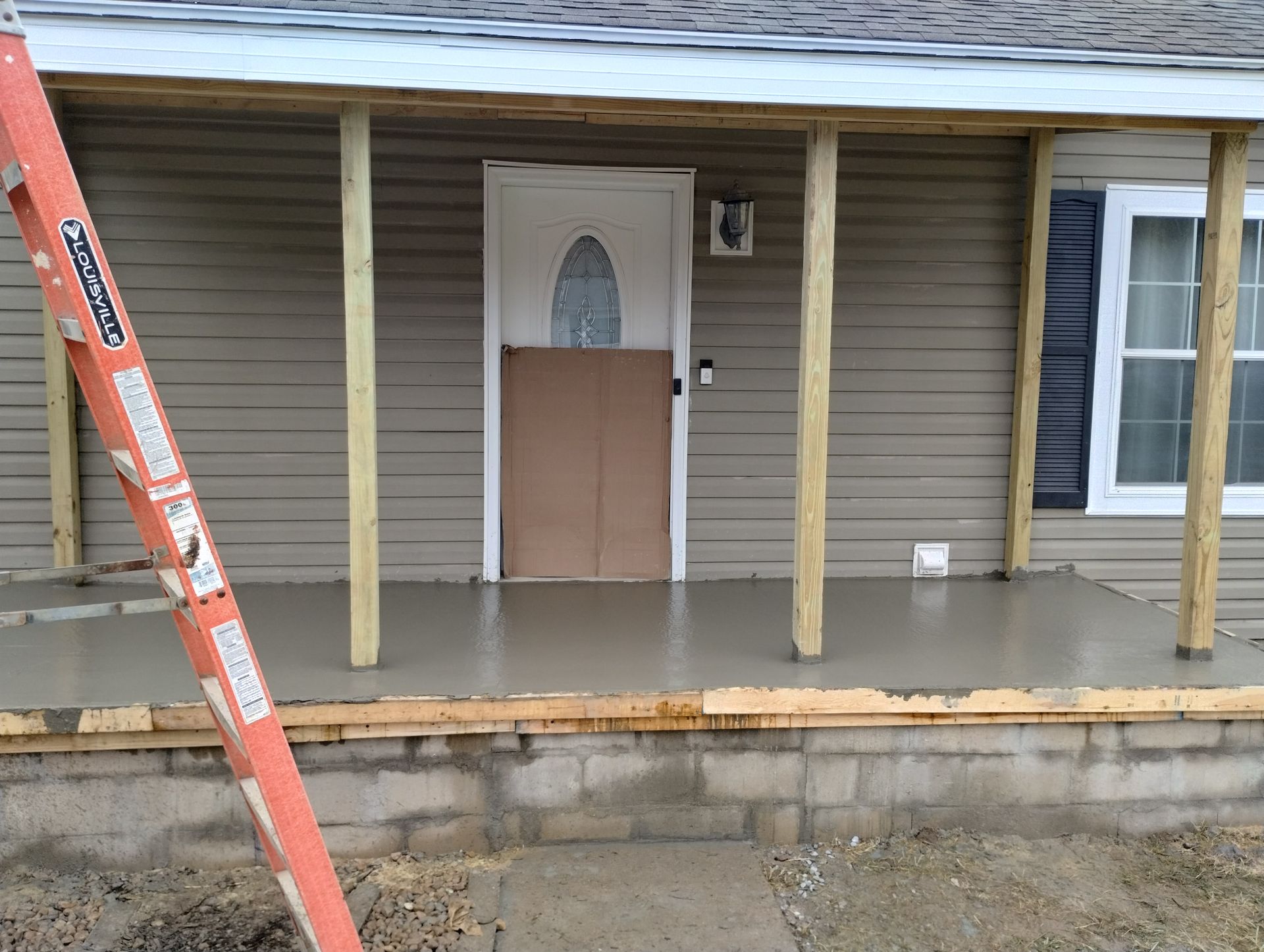 A ladder is leaning against a porch of a house