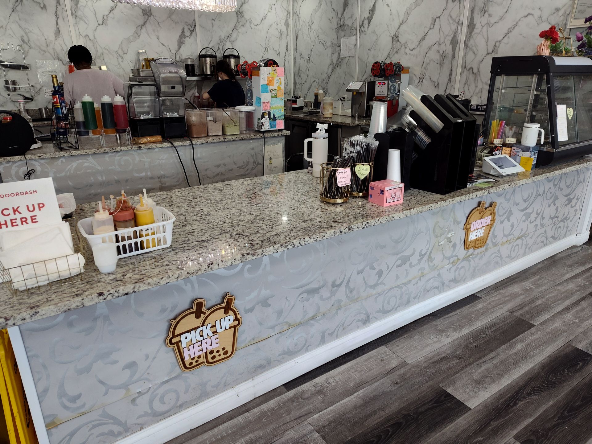 A counter in a restaurant with a sign that says ' order here ' on it.