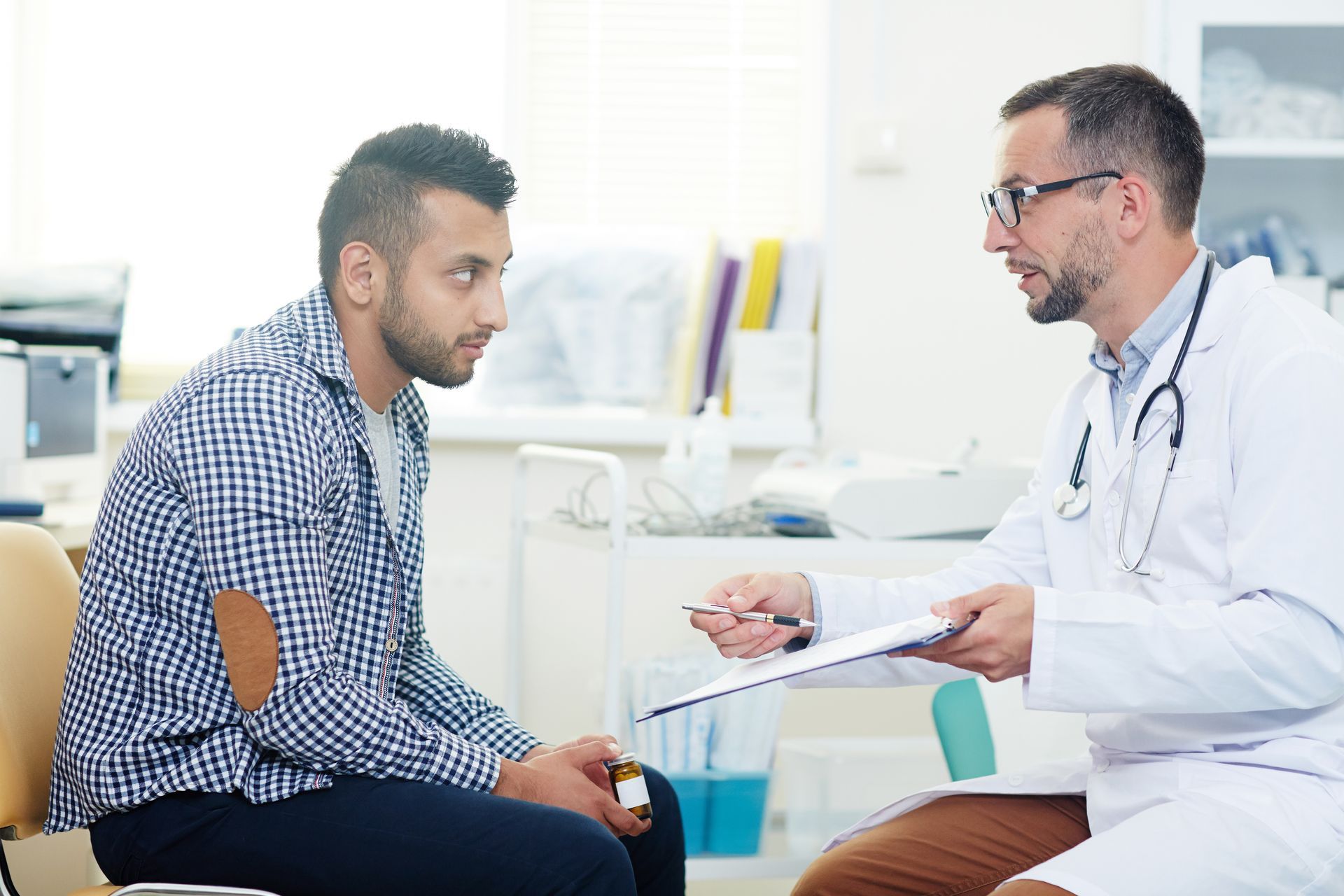 A doctor is talking to a patient who is sitting in a chair.