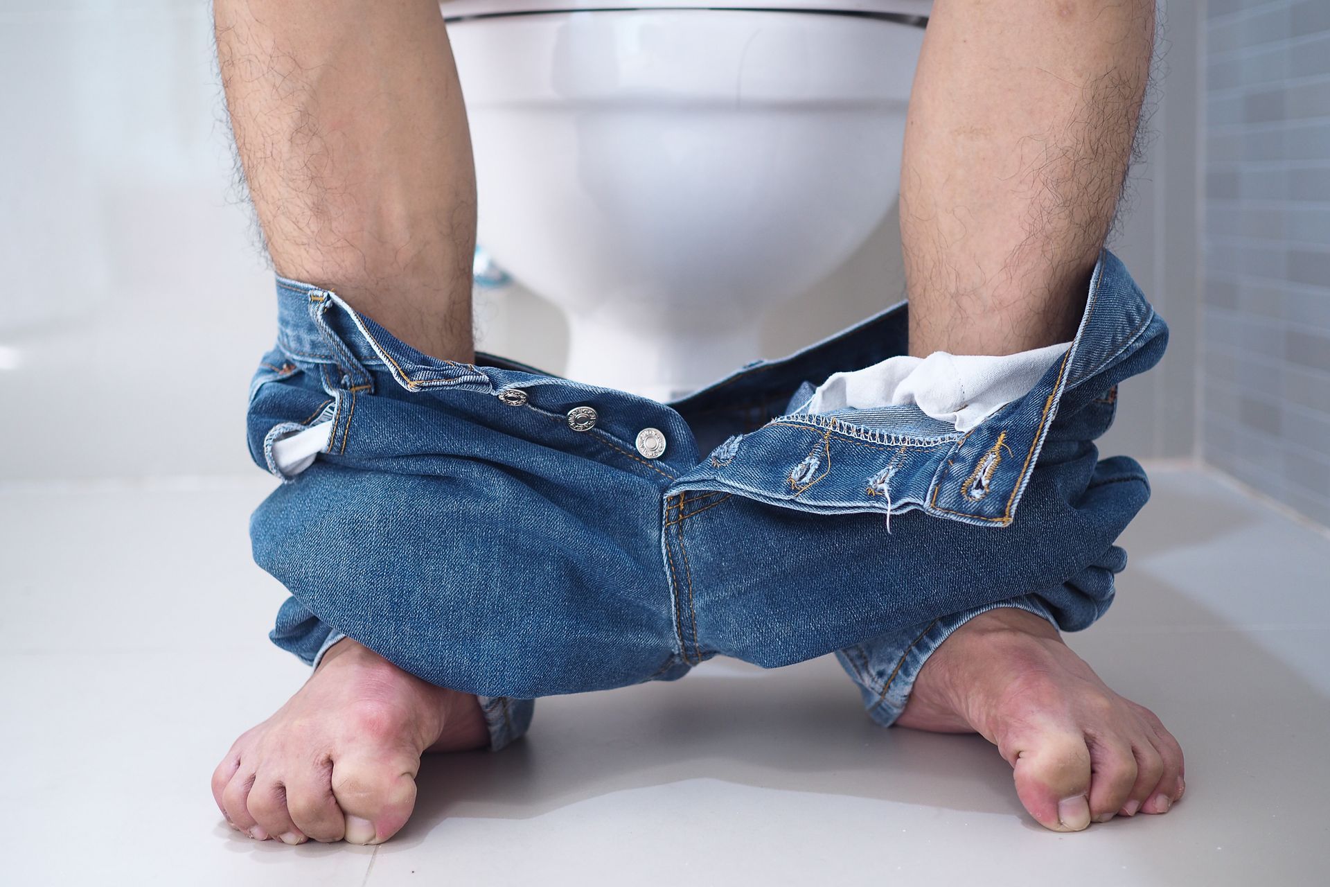 A man is sitting on a toilet with his pants down.