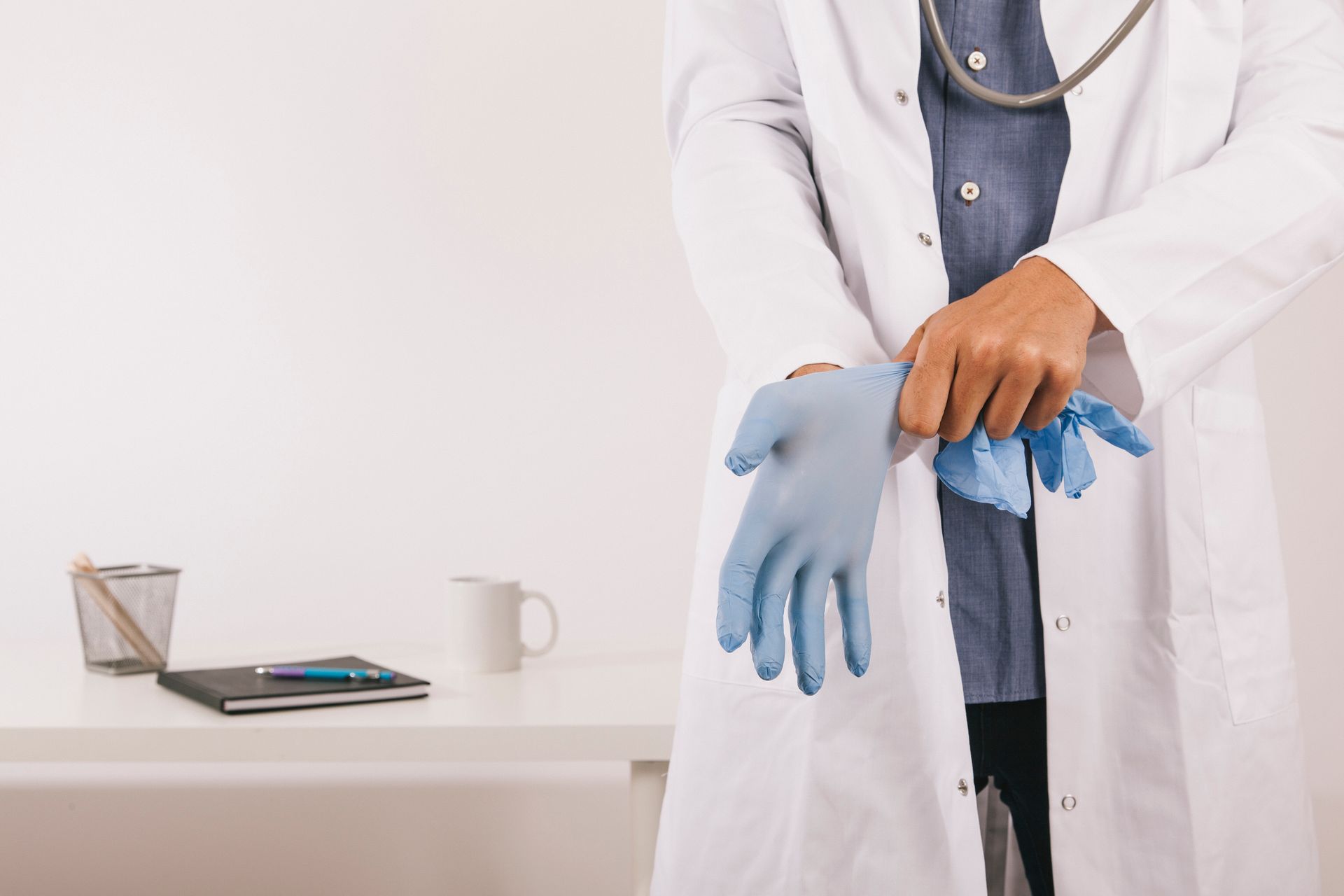 A doctor is putting on a pair of blue gloves.