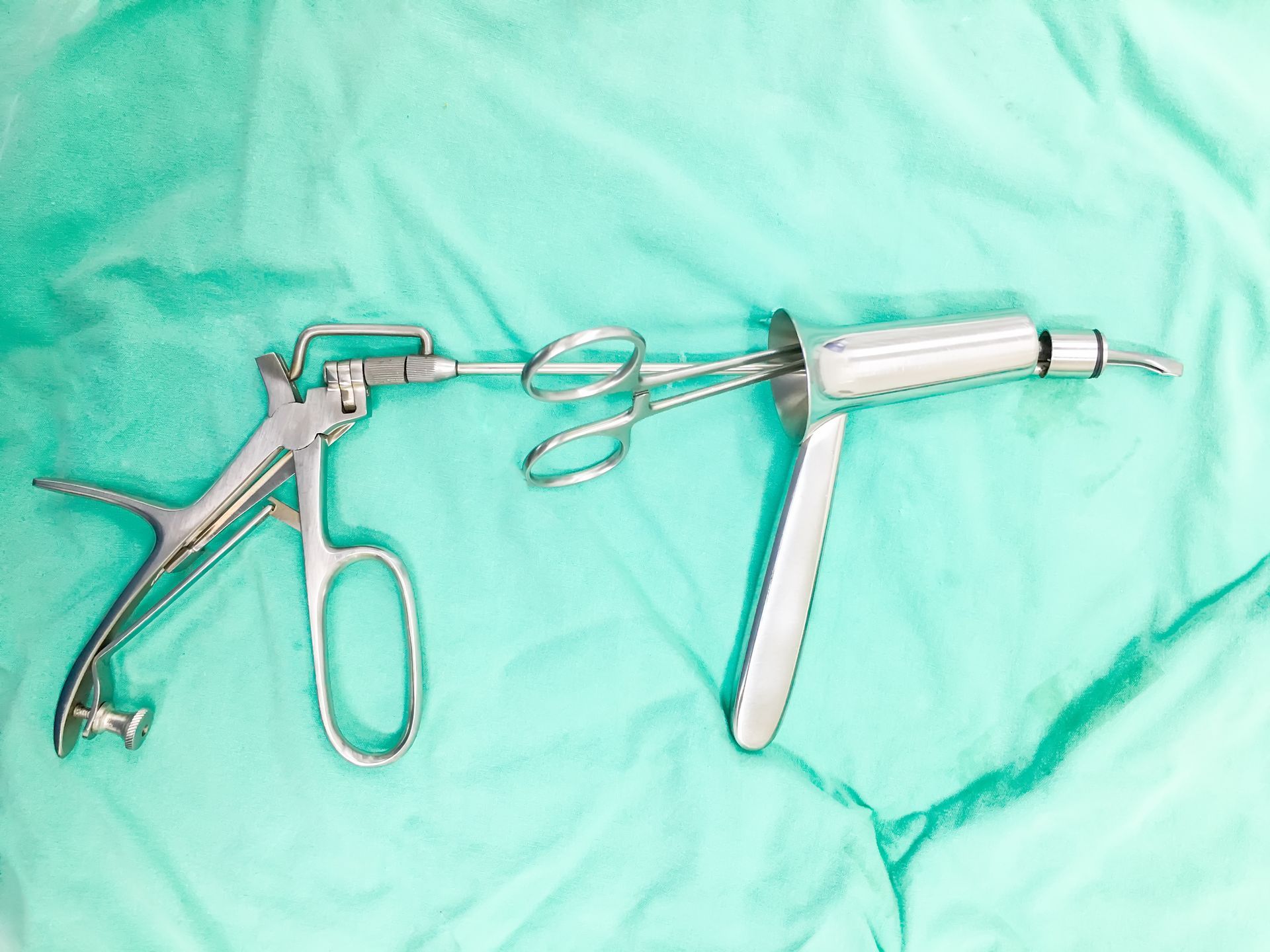 A pair of surgical instruments are laying on a green cloth.