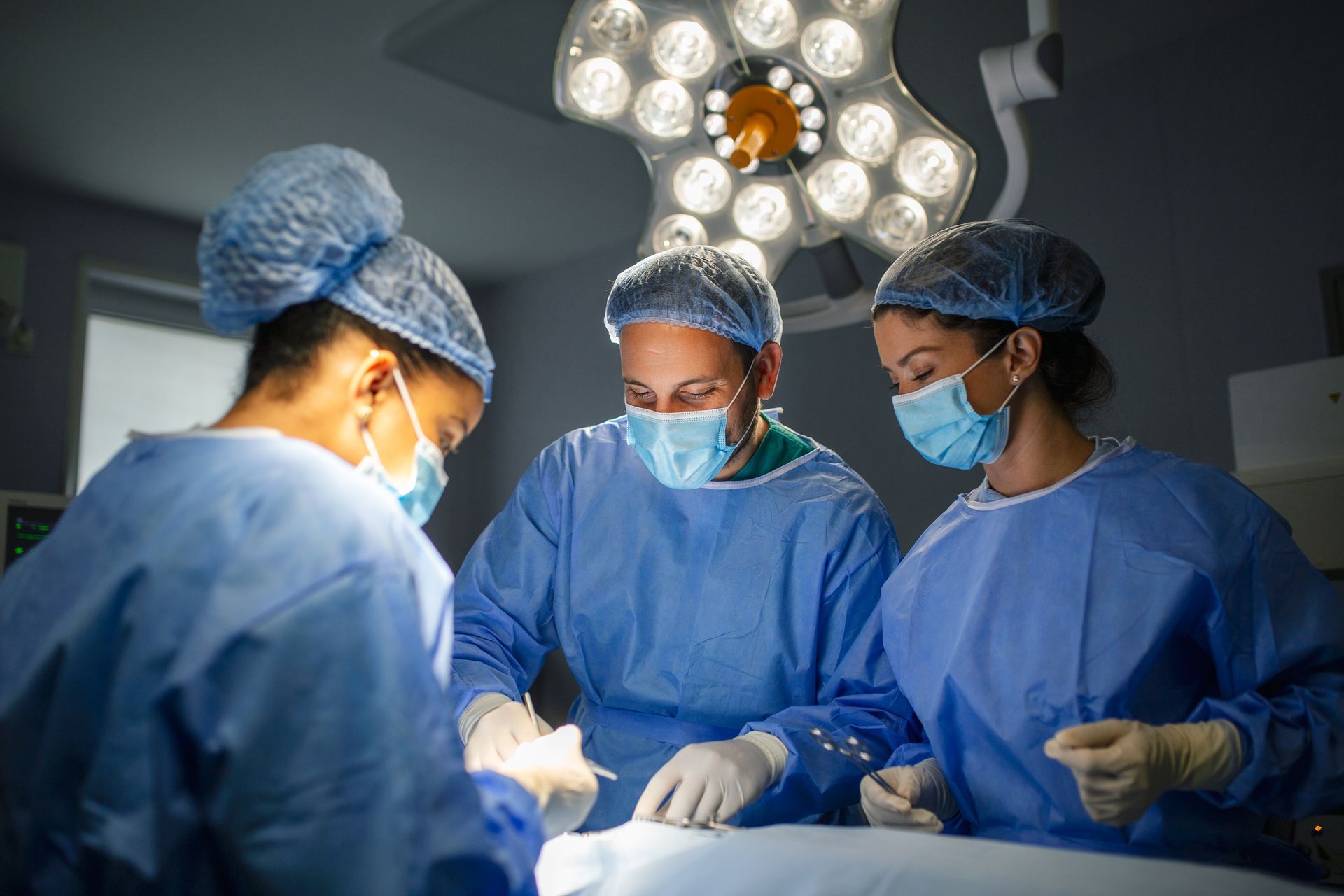 A group of surgeons are operating on a patient in an operating room.