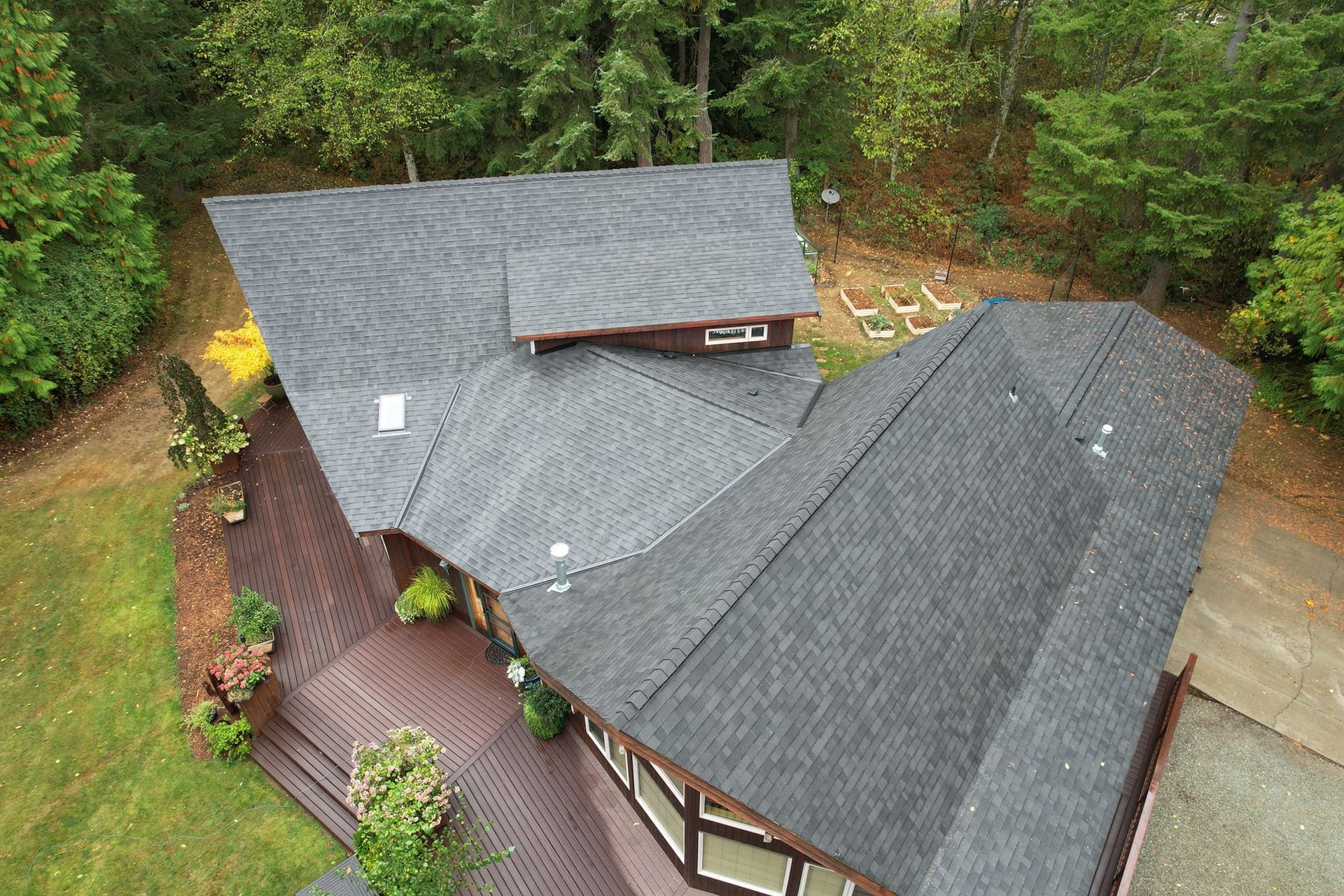 An aerial view of a house with a large roof surrounded by trees from Washington Roofing Services near Arlington WA