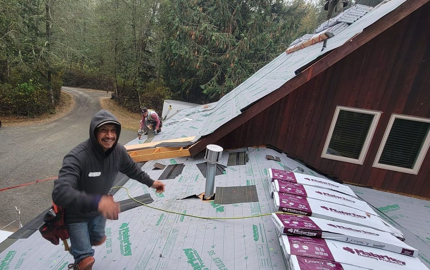 A man is working on the roof of a house from Washington Roofing Services near Arlington WA