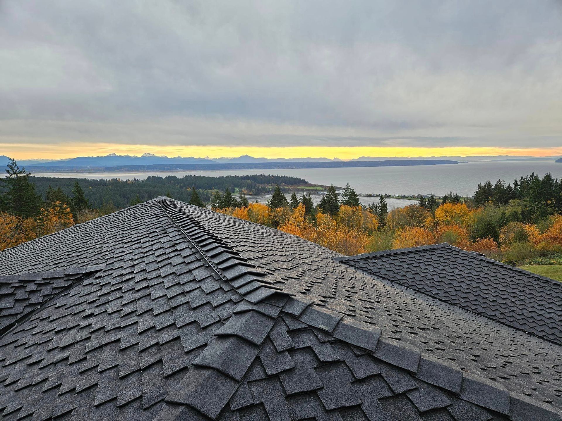 The roof of a house with a view of the ocean and mountains from Washington Roofing Services near Arlington WA