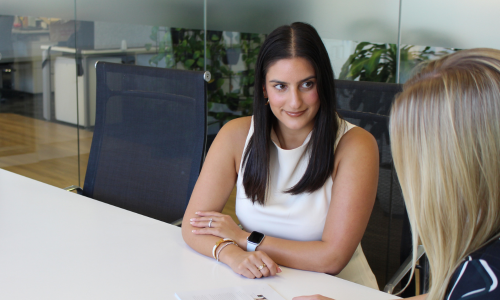 Two women are sitting at a table having a conversation.