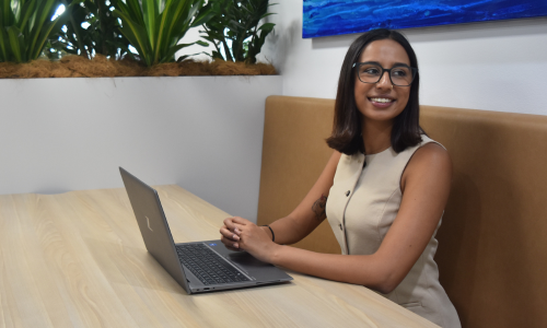 A woman is sitting at a table with a laptop on it.