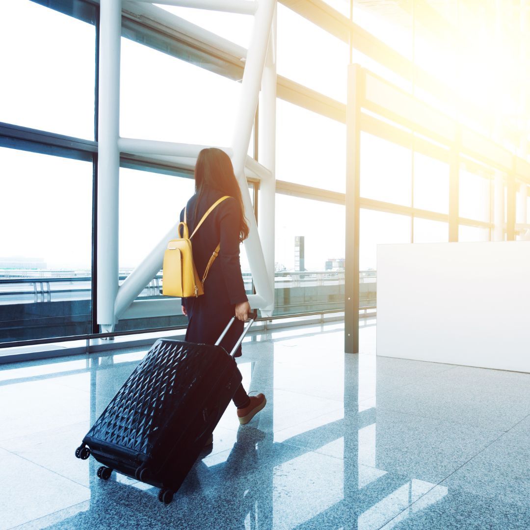 A woman is walking with a suitcase in an airport.