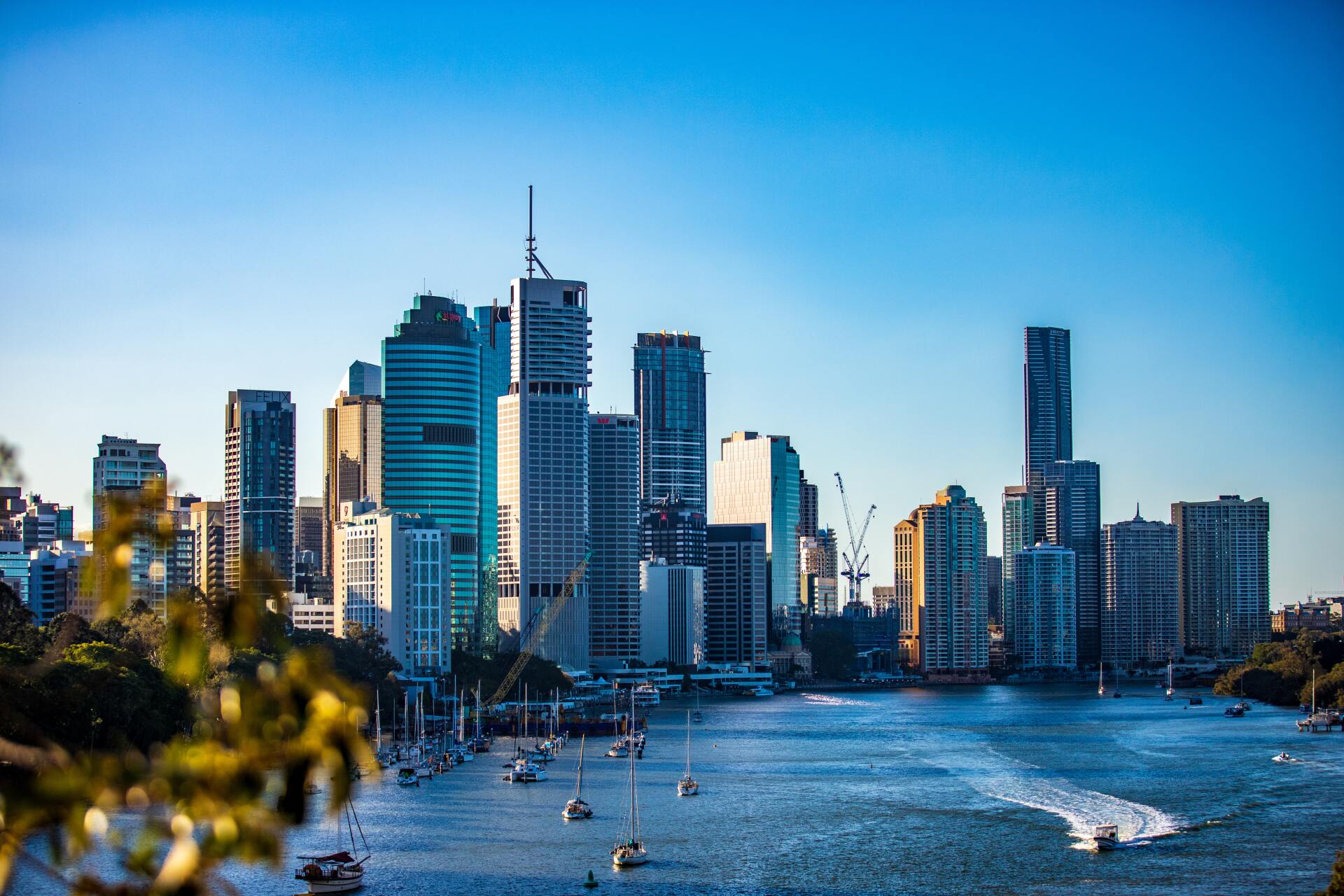 A city skyline with boats in the foreground and a river in the background.