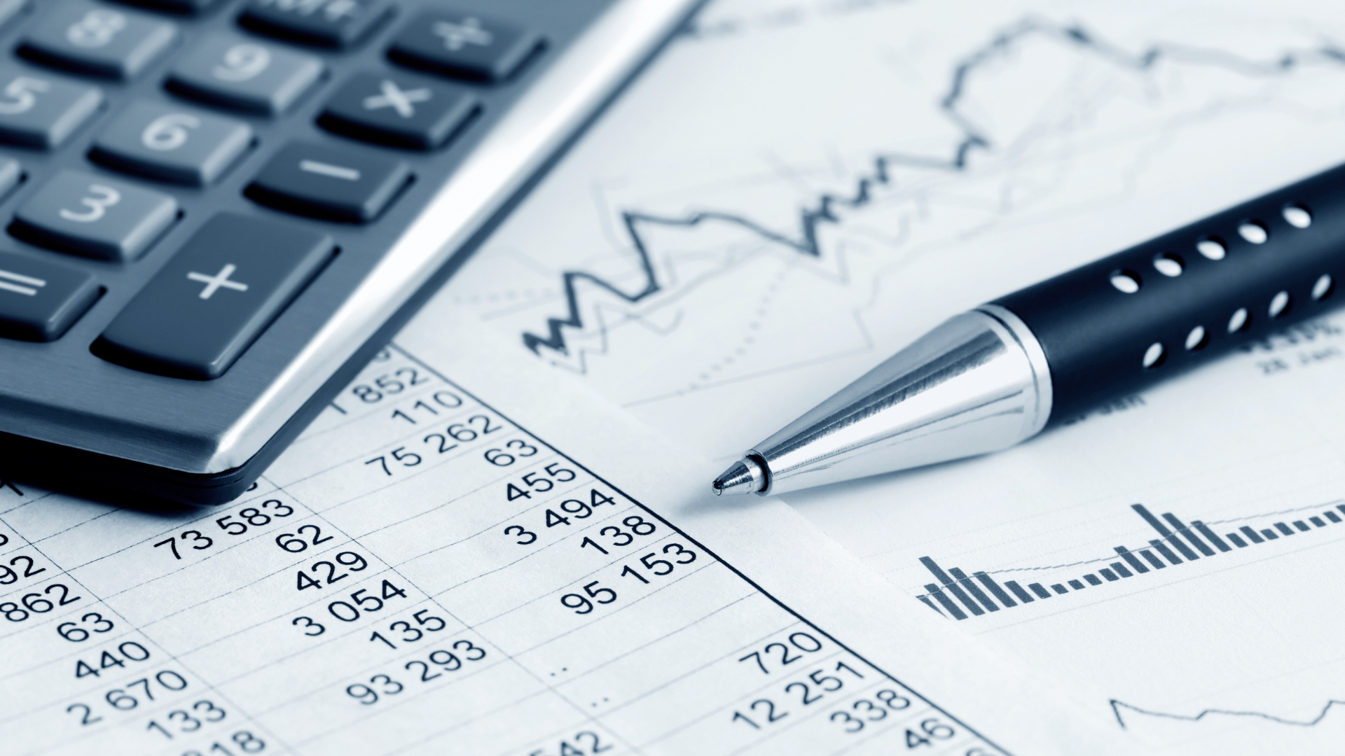 Calculator, pen, and financial documents with numbers and a graph.