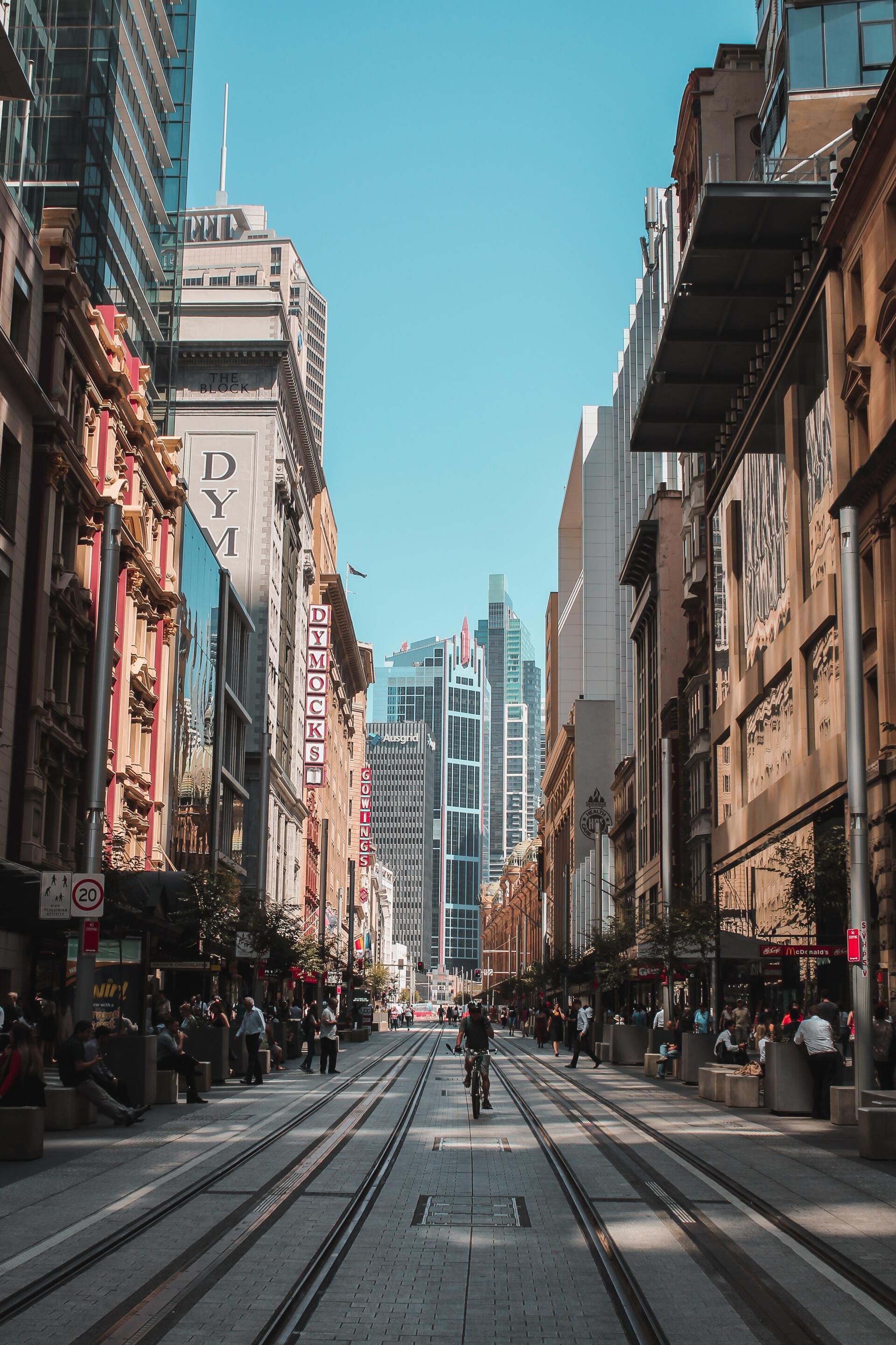 A man is walking down a narrow street in a city.