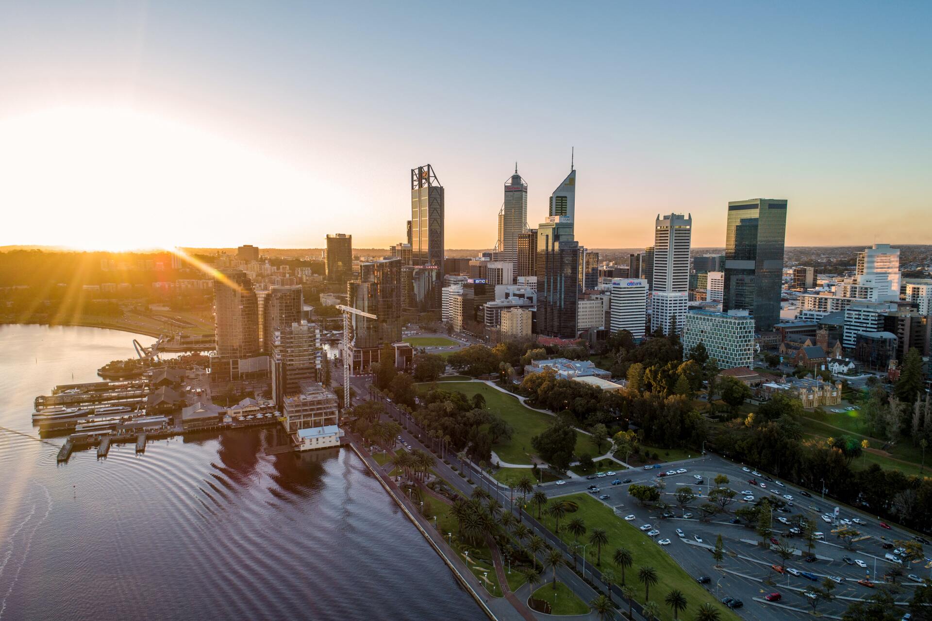An aerial view of a city skyline at sunset with a lake in the foreground.