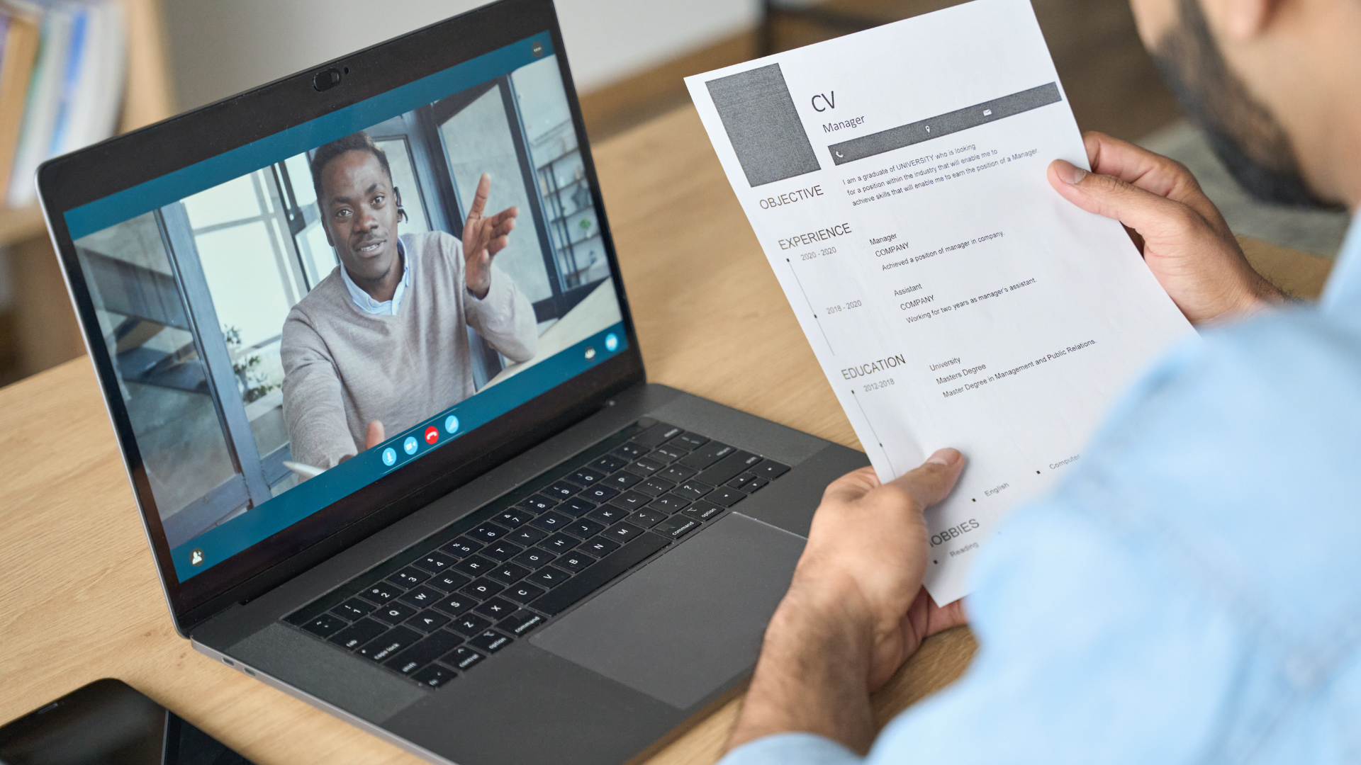 a man is holding a resume in front of a laptop computer .