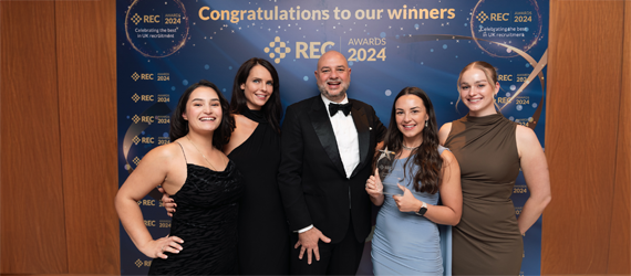 A group of people are posing for a picture in front of a wall that says congratulations to our winners.