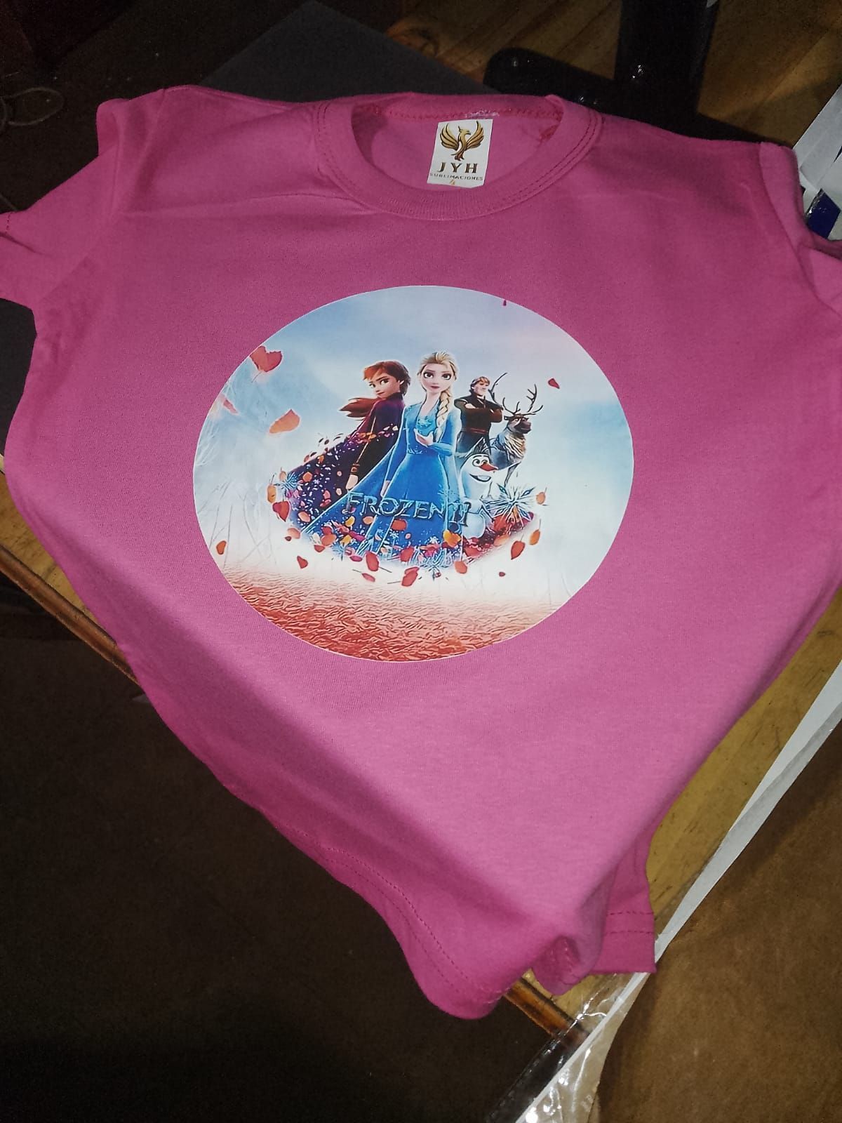 Camiseta rosa con un gráfico redondo de Anna, Elsa y Kristoff de Frozen.