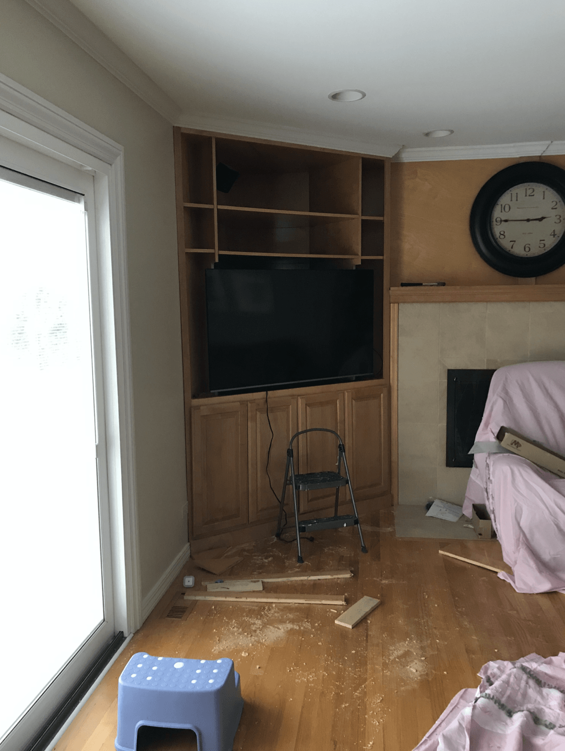 A living room with a clock on the wall and a television on the wall.