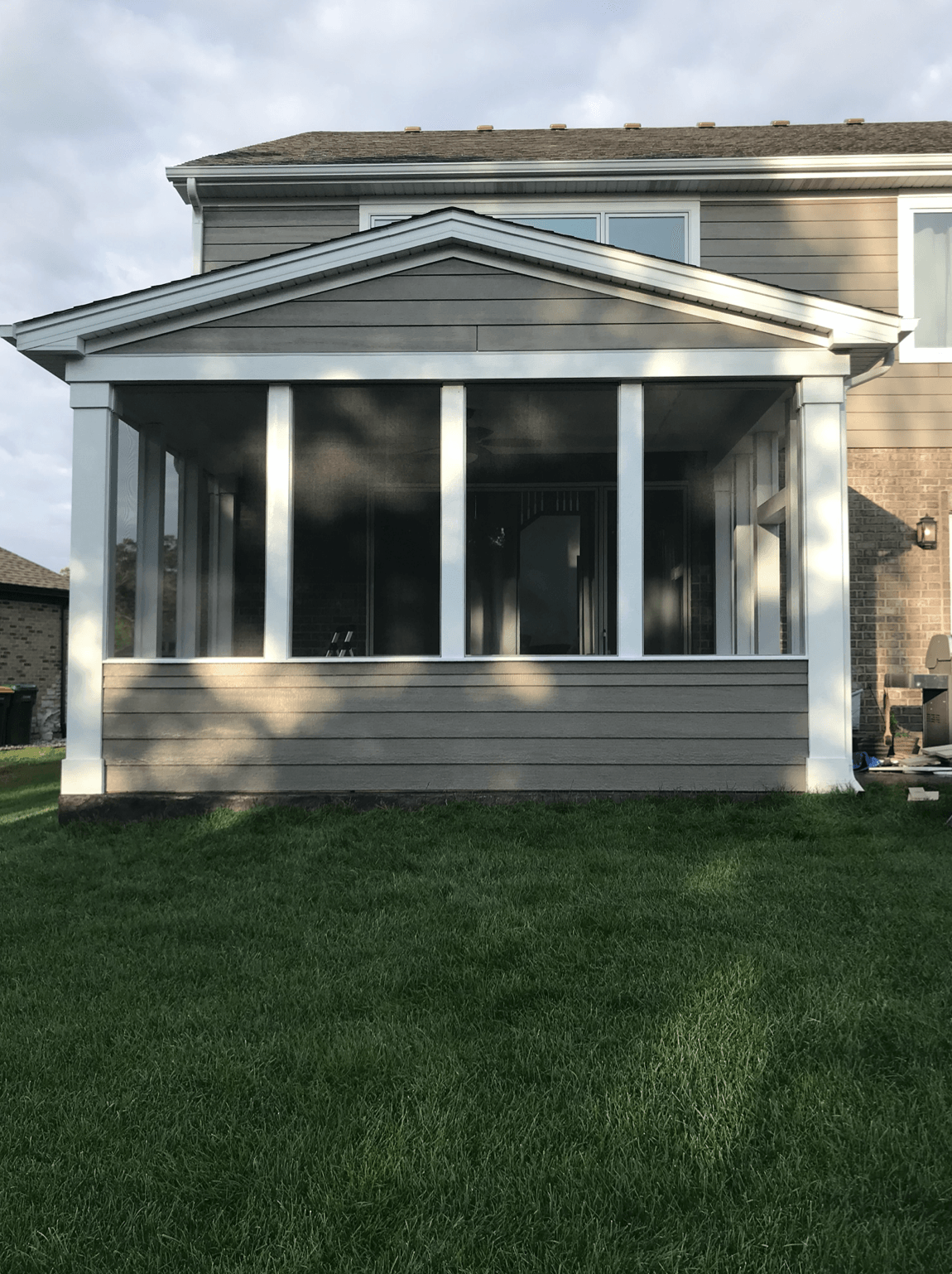 A screened in porch on the side of a house.