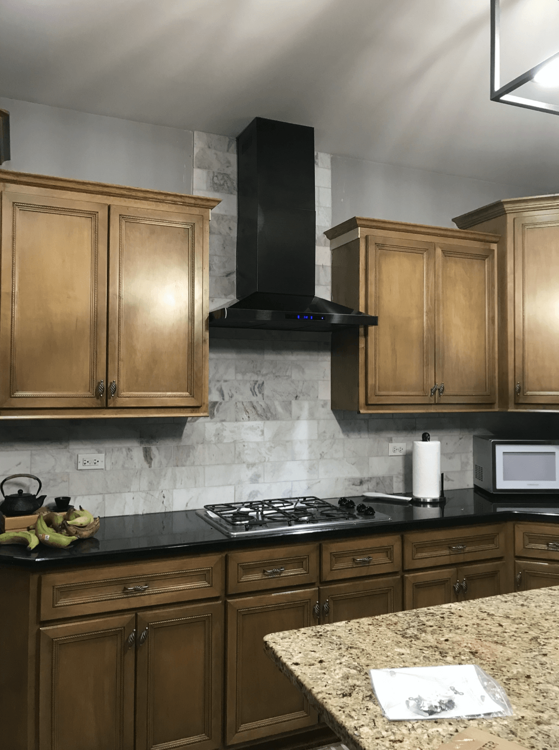 A kitchen with wooden cabinets , granite counter tops , a stove and a microwave.