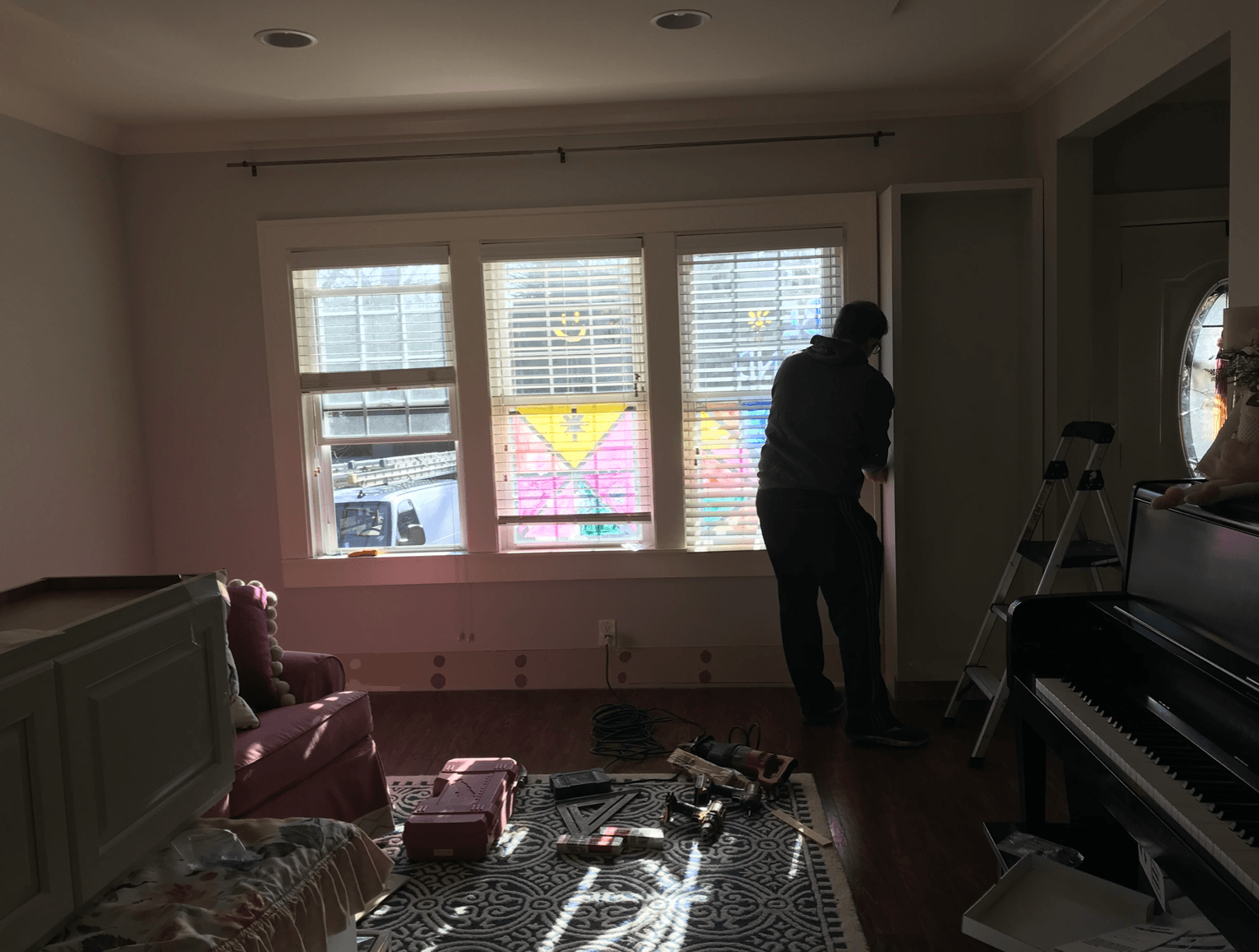 A man is standing in a living room next to a piano.