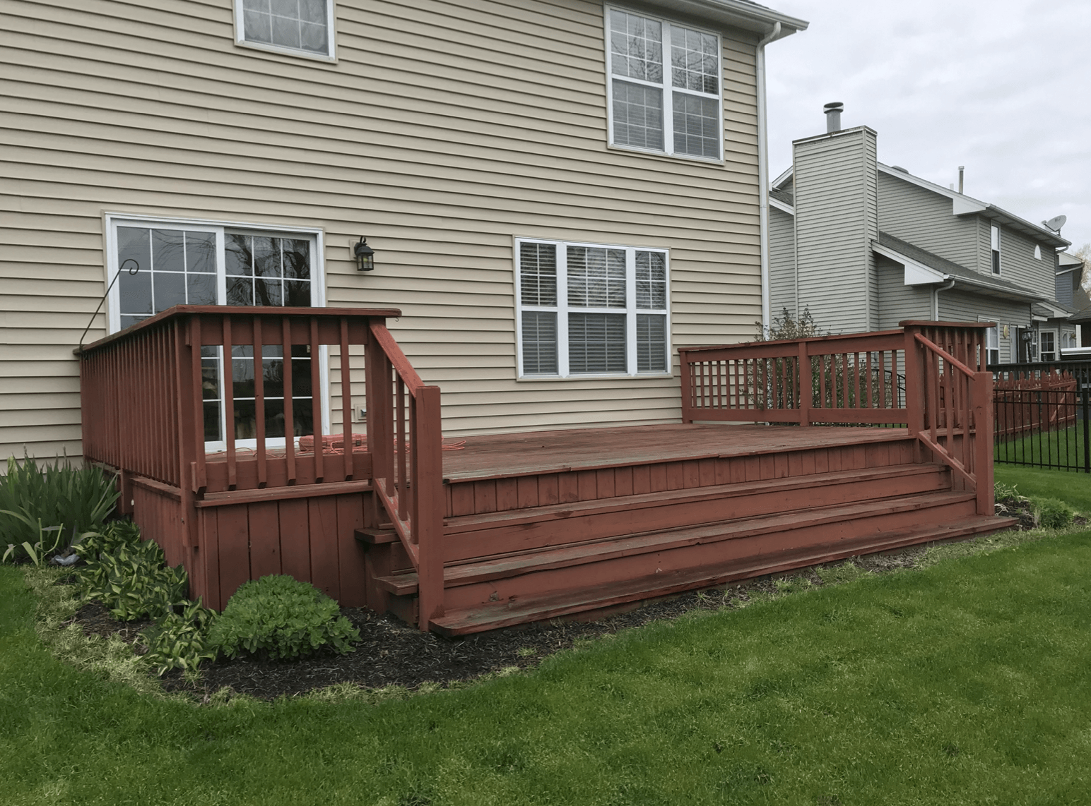 A large wooden deck is in front of a house.