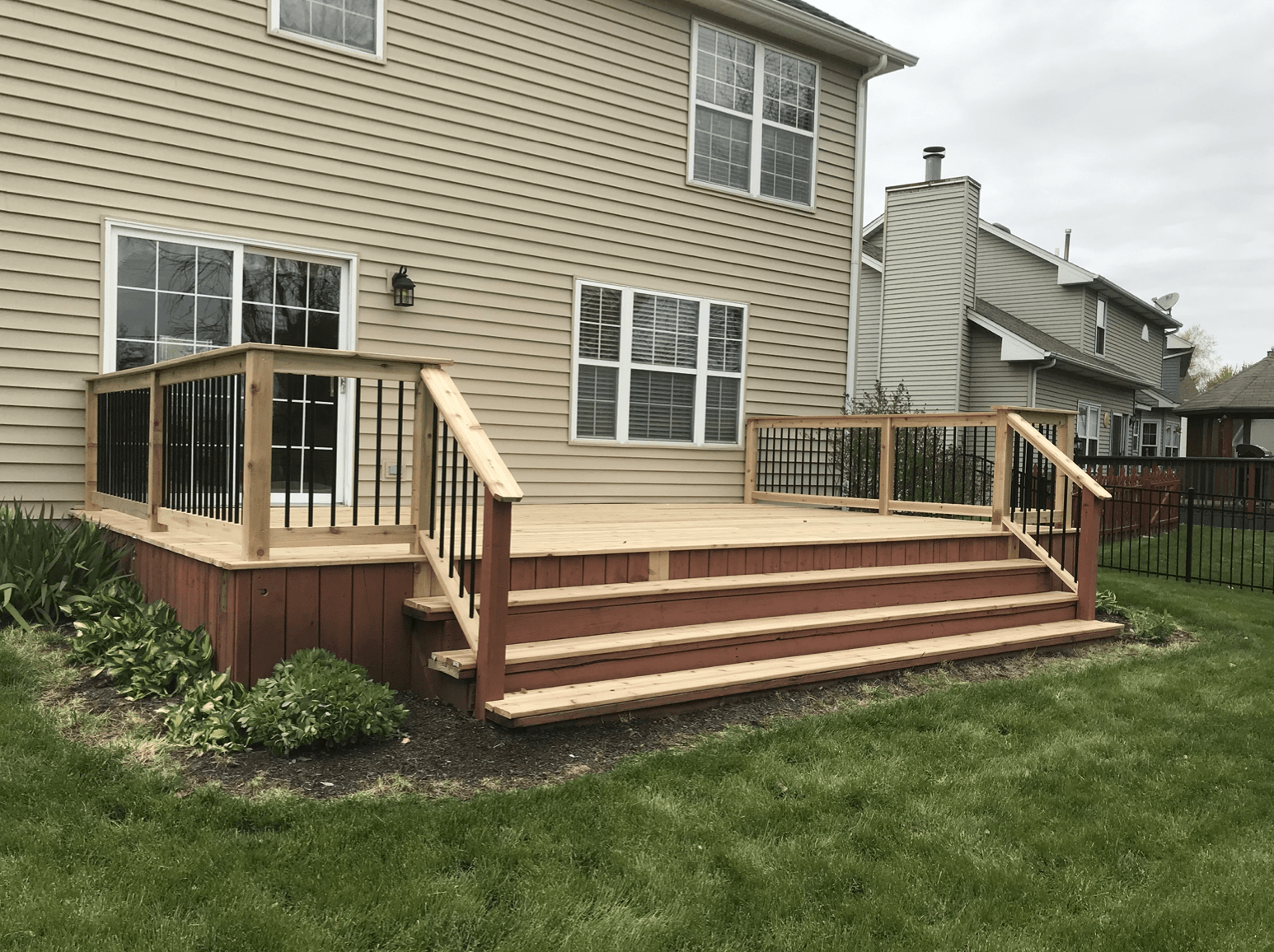 A wooden deck with stairs in front of a house.