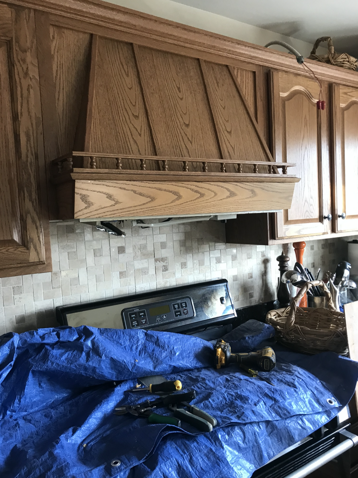 A blue tarp is covering a stove top oven in a kitchen.