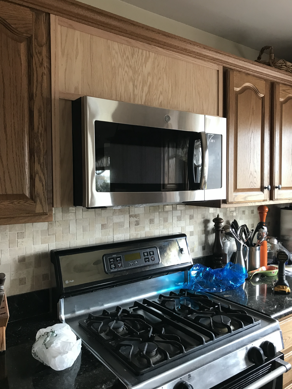A kitchen with a stove , microwave , and cabinets.